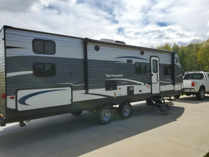 Spacious Springdale travel trailer RV with extended slide-out, hitched to a truck. Ideal for your next RV rental adventure!. Keystone 27BHS 2017