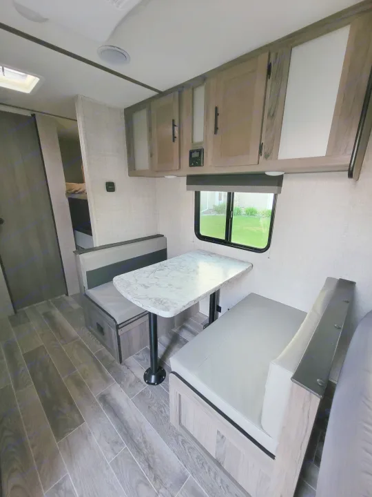 Clean RV rental interior: dinette with modern table, comfy benches, overhead cabinets, and bunk beds.. Gulf Stream Ameri-Lite Super Lite 2021