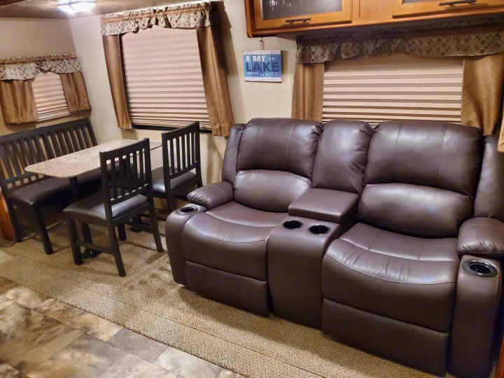 Spacious RV rental interior featuring a dinette with bench seating & chairs, plus a comfy reclining sofa with cup holders.. Forest River Surveyor 2015