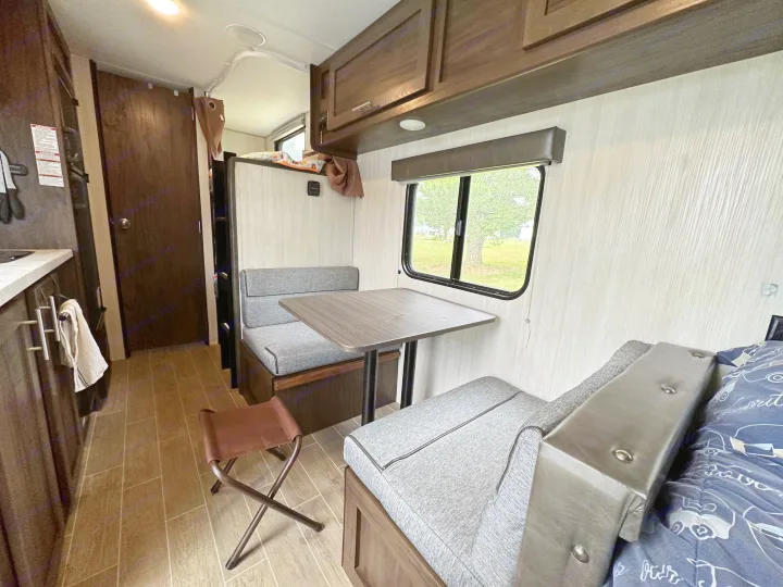 RV rental interior: a cozy and functional space featuring a dinette, compact kitchen, overhead bunk, and window view.. Forest River Cherokee Wolf Pup 2020