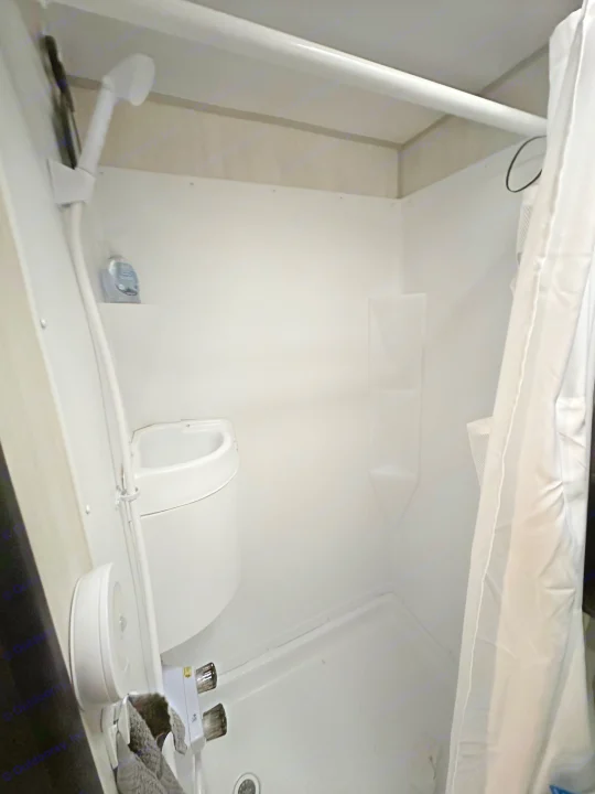 Compact white RV rental bathroom with a shower, wall-mounted sink, and shower curtain. Functional for travel.. Forest River Cherokee Wolf Pup 2020