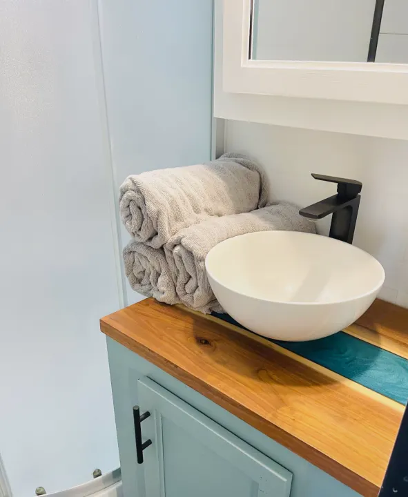 Modern RV rental bathroom: vessel sink, black faucet, wood & resin counter with rolled towels. Compact and stylish.. Forest River Cherokee Grey Wolf 2019