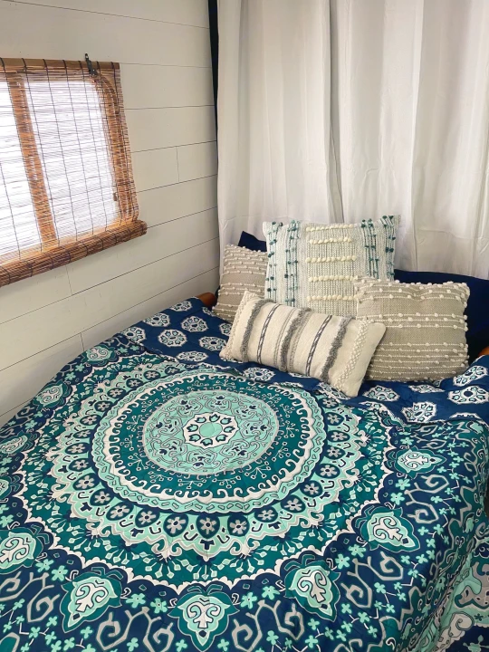 This comfy **rv rental** features a bed with intricate mandala bedding, inviting textured pillows, and natural window blinds.. Forest River Cherokee Grey Wolf 2019