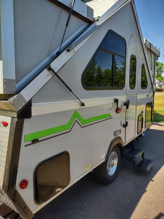 This rv rental, a light gray A-frame pop-up camper, shows its unique folding design and green accent.. A Liner A Liner Popup Trailer 2022
