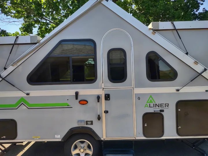 Explore a compact gray A-Liner A-frame pop-up camper, an ideal RV rental. Green accents and windows visible.. A Liner A Liner Popup Trailer 2022