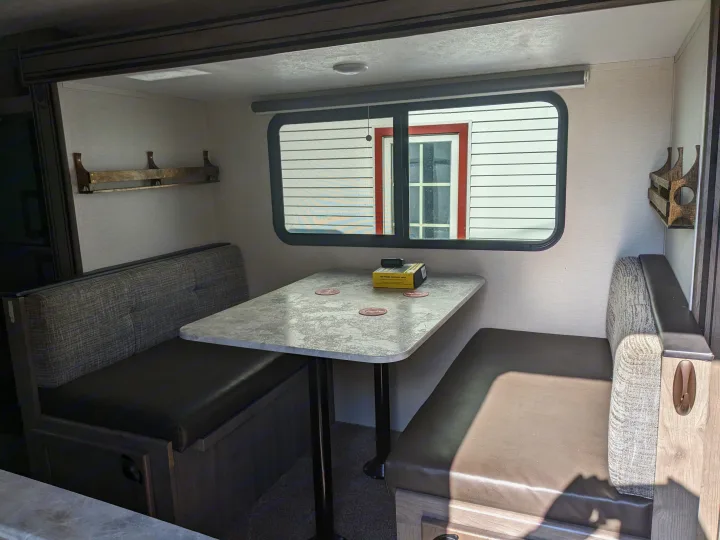 **RV rental dinette** featuring comfortable bench seating, a large table, and a window looking out, perfect for meals and relaxation.. Coachmen Apex Nano 2021
