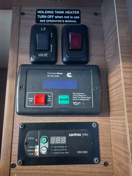 An RV rental's main control panel, featuring a Cummins Onan generator, Xantrex inverter displays, plus tank heater & LP valve switches.. Winnebago View 2015
