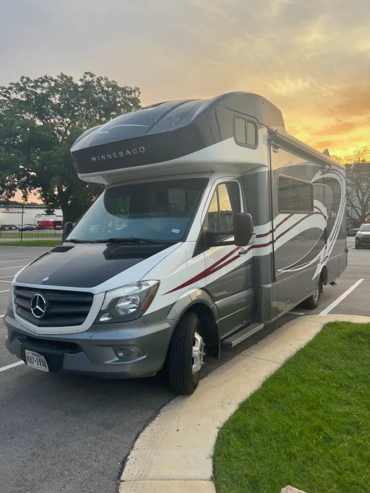 A spacious Winnebago RV rental, a Mercedes-Benz Sprinter motorhome, parked in Texas under a warm sunset sky.. Winnebago View 2015