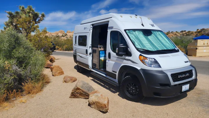 White Winnebago rv rental van parked in Joshua Tree National Park, surrounded by desert plants and rocks.. Winnebago Solis 2023