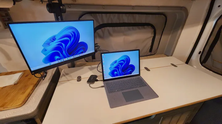 RV rental: a compact mobile office featuring a laptop, external monitor, and folding table. Ideal for remote work on the go.. Winnebago Solis 2023