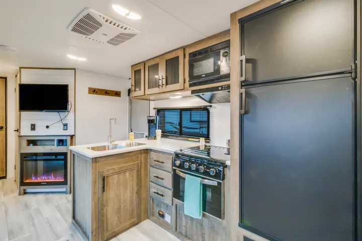 Spacious rv rental interior featuring a modern kitchen with stove, fridge, microwave, and living area with TV & fireplace.. Heartland RVs Pioneer 2022