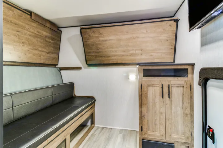 RV rental interior showcasing a cozy bench seat, pull-down bed, and wood storage cabinets, perfect for travel.. Heartland RVs Pioneer 2022