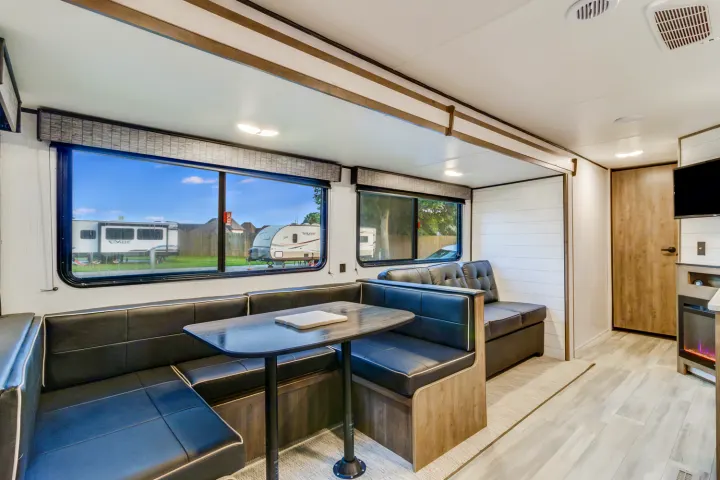 Modern rv rental living space with a dining booth, lounge seating, and entertainment center inside.. Heartland RVs Pioneer 2022