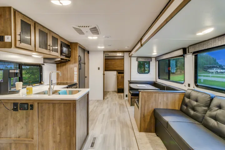 This RV rental showcases a bright interior with a kitchen island, dinette, and sofa. Ideal for comfortable travel.. Heartland RVs Pioneer 2022