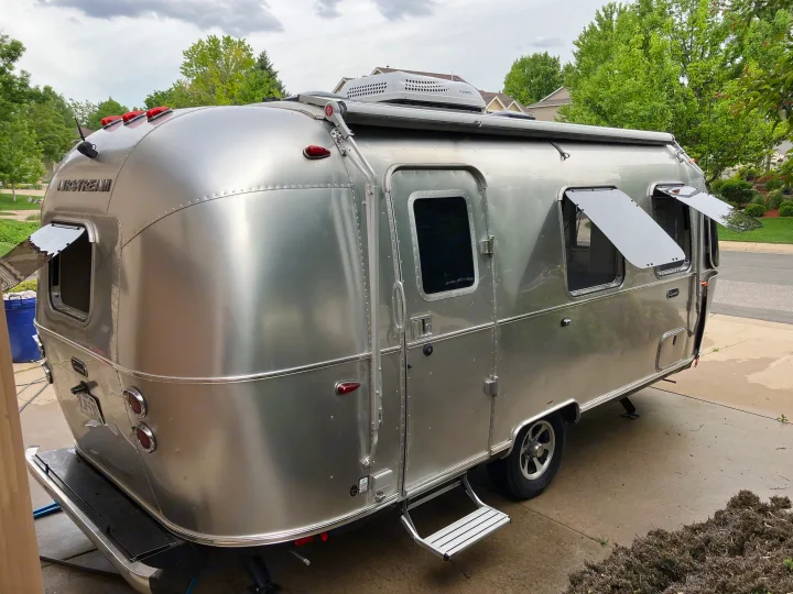 Sleek silver Airstream RV, ready for an RV rental journey, parked with open windows and deployed steps on a paved surface.. Airstream Caravel 2022