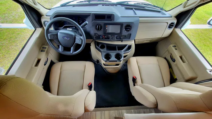 RV rental: Inside the spacious cockpit with Ford steering wheel, dashboard controls, and tan front seats.. Thor Freedom Elite 2021