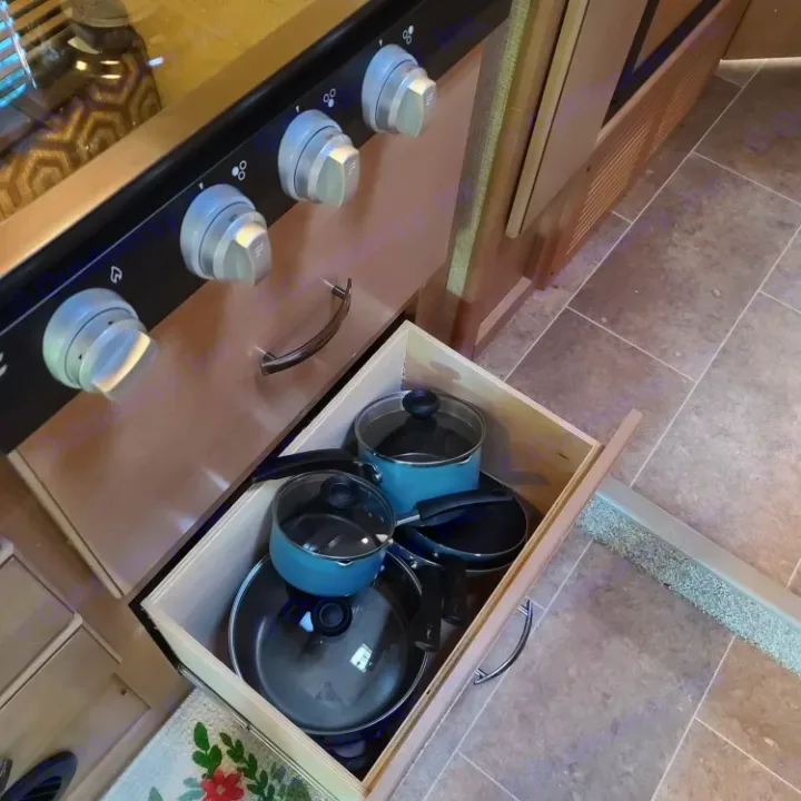 RV rental kitchen: Open drawer reveals neatly stacked pots and pans below the stove, ideal for cooking meals.. Thor Motor Coach Chateau 2019