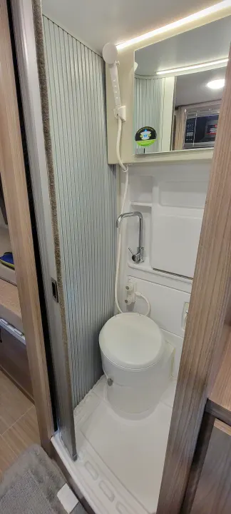 Compact RV rental wet bath with toilet, handheld shower, and faucet for efficient camper living.. Thor Sequence 2021