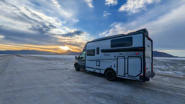 This sleek RV rental, an adventure motorhome, is parked at sunset on a vast, flat landscape.. Winnebago Ekko 2023