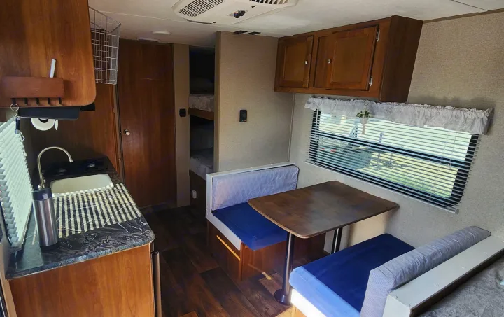 Inside an **rv rental**, showcasing a kitchen, dinette, and bunk beds. A compact, inviting space designed for comfortable travel.. Keystone RV Summerland Mini 2017