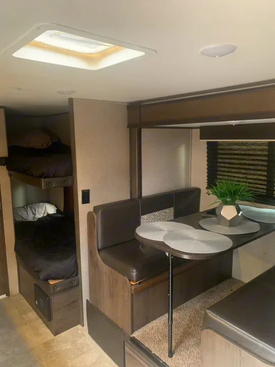 Inside a comfortable **rv rental**: a bright dinette area with seating and table, opposite side shows two bunk beds.. Jayco Jay Flight SLX 2020