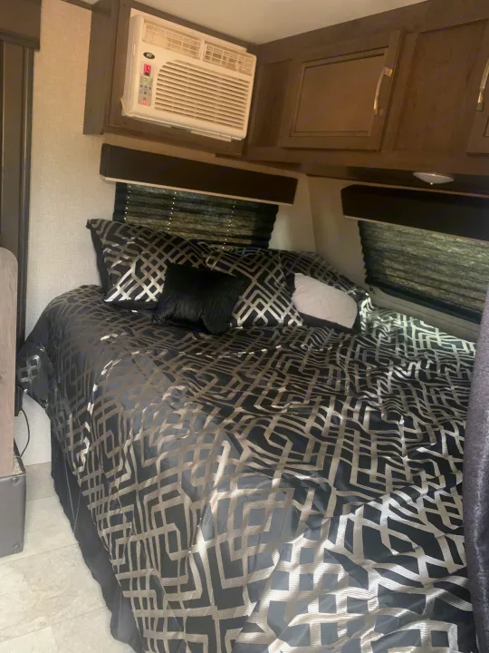 Cozy RV rental bedroom featuring black and silver geometric bedding, overhead cabinets, and AC unit set to 64.. Jayco Jay Flight SLX 2020