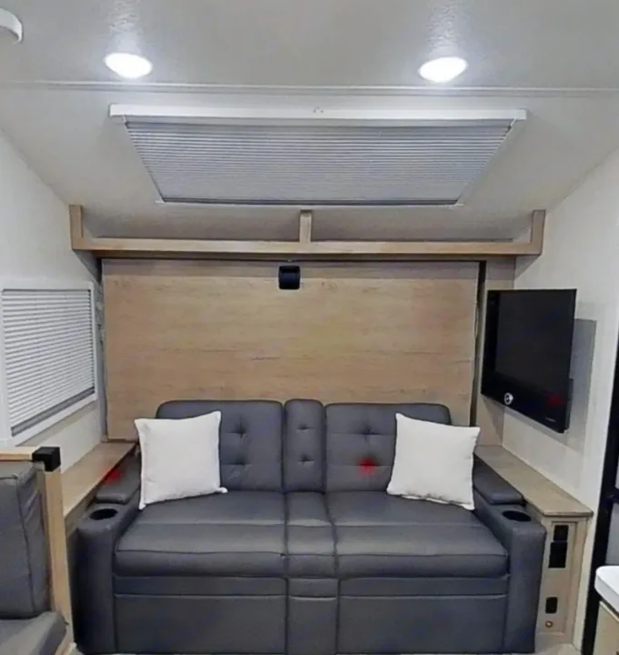 RV rental: Cozy interior showing a gray sofa, convertible bed, TV, and side storage, ideal for compact living.. Ember 191MBD 2022