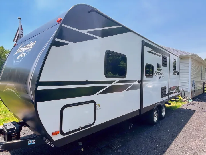 A clean white and black Imagine XLS travel trailer RV, ready for **rv rental**. This recreational vehicle is perfect for adventures.. Grand Design Imagine XLS 2022