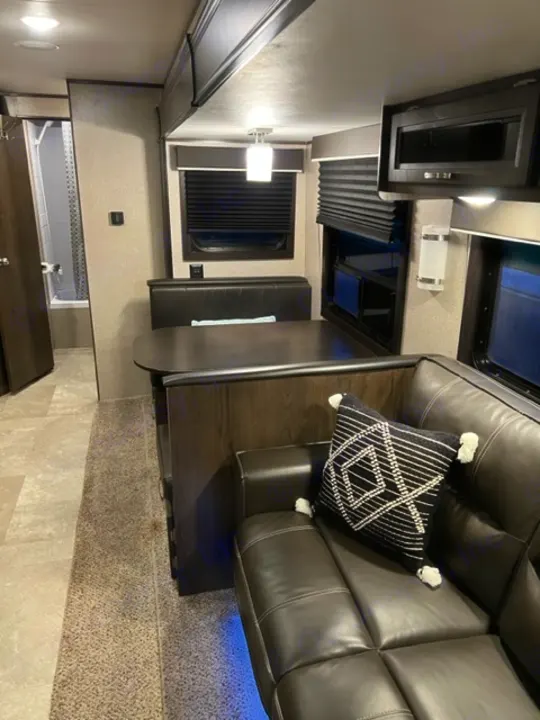 Cozy RV rental interior with modern dark sofa, patterned pillow, dinette, and ambient lighting. Ready for travel!. Jayco Jay Flight SLX Rocky Mountain Edition 2021