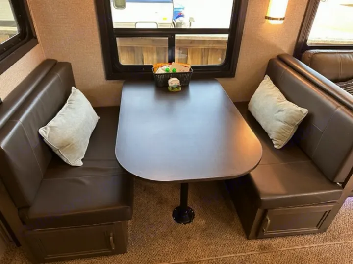 Cozy RV rental dinette with brown benches, a dark table, and windows. Ideal for dining on a trip.. Jayco Jay Flight SLX Rocky Mountain Edition 2021