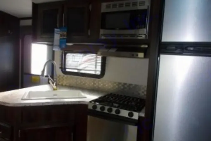 RV rental kitchen: modern sink, stove, microwave, and fridge. Perfect for travel comfort and camping adventures.. Jayco White Hawk 2018