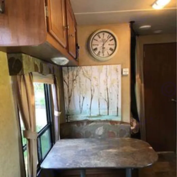 RV rental interior: A comfortable dinette with a table, bench seating, overhead cabinets, and wall art.. Jayco Jay Flight Swift 2013