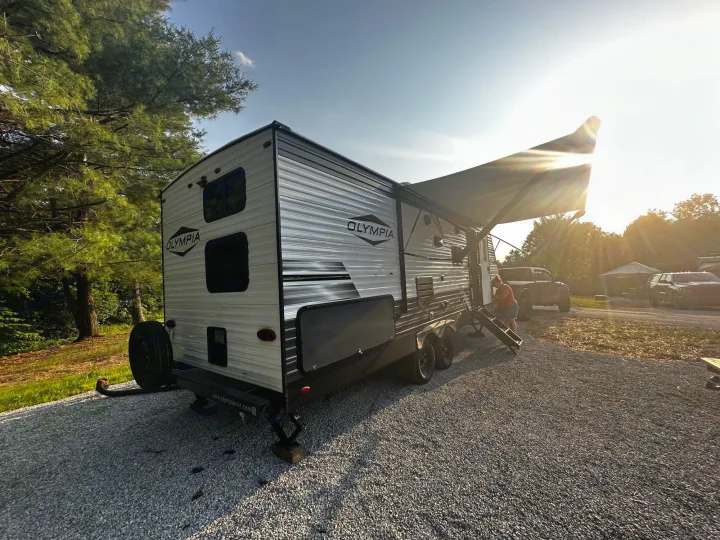 An Olympia RV rental parked on a sunny gravel lot with its awning extended, perfect for a camping adventure.. Highland Ridge RV Olympia 2022