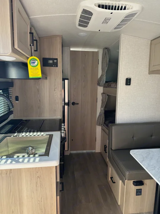 View inside a well-appointed rv rental featuring a kitchen, dinette seating, and cozy bunk beds.. Forest River Flagstaff E-Pro 2023