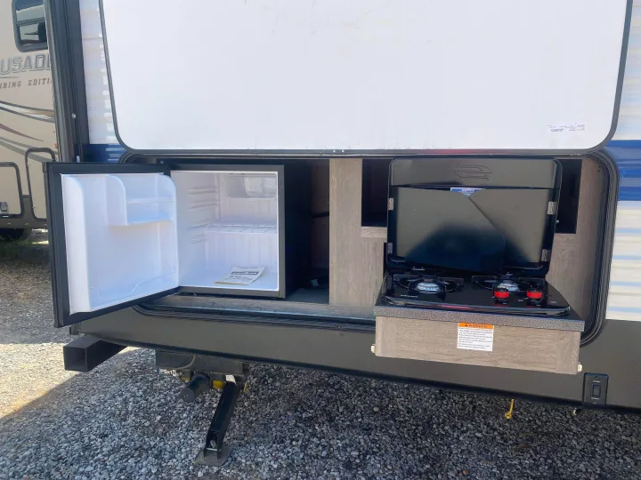 This RV rental features an open outdoor kitchen with a mini-fridge and two-burner cooktop, ideal for camping adventures.. Keystone RV Springdale 2021