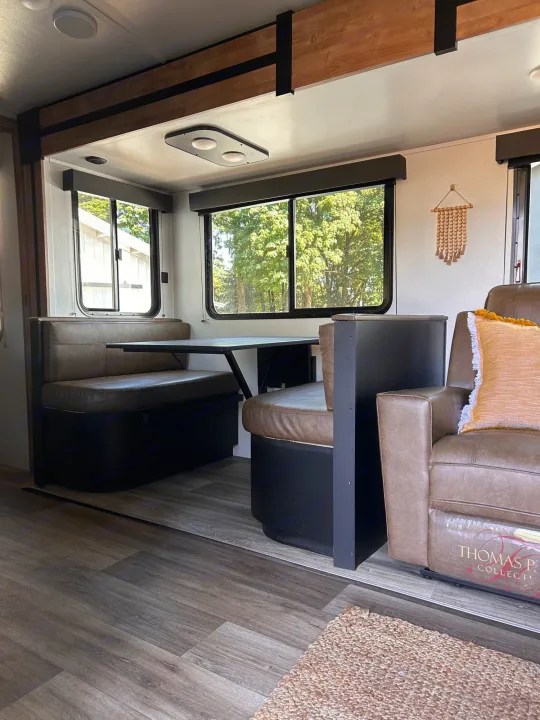 RV rental: Spacious interior with a dinette booth, large windows, and comfy recliner, featuring wood-look floors.. Keystone RV Outback Ultra-Lite 2022