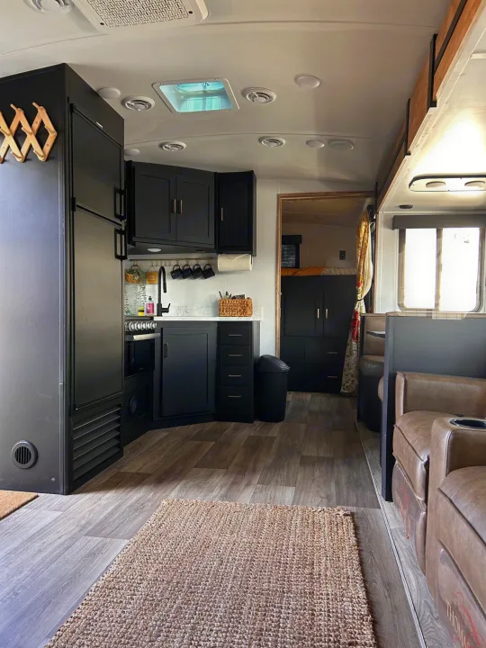 Spacious RV rental interior featuring a modern black kitchen, cozy living area, and bedroom, perfect for travel.. Keystone RV Outback Ultra-Lite 2022