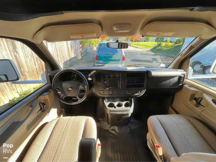 Interior of an RV rental van's cockpit, featuring the steering wheel, dashboard, and front seats. Through windshield view.. Coachmen Leprechaun 2015