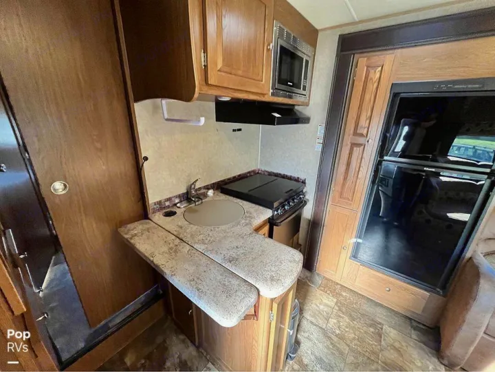 This RV rental boasts a compact kitchen with a sink, stove, microwave, and large refrigerator, perfect for travel cooking.. Coachmen Leprechaun 2015
