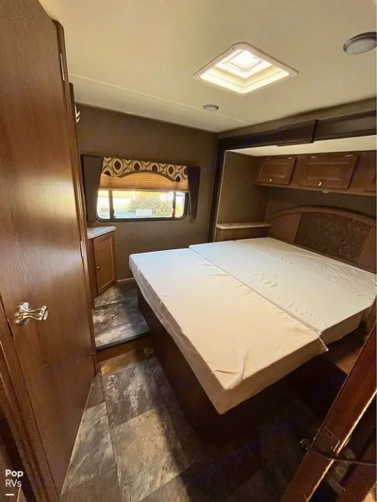 Explore this RV rental bedroom: a cozy interior with a spacious bed, window, overhead storage, and ceiling skylight.. Coachmen Leprechaun 2015