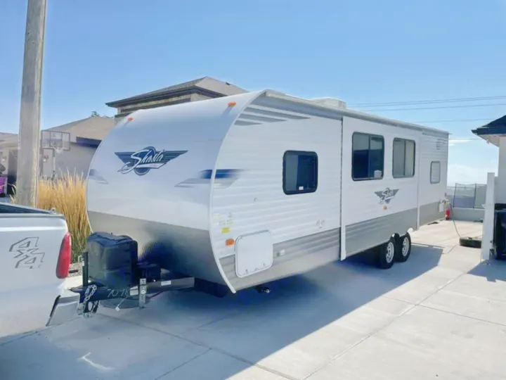 Clean white Shasta travel trailer, an ideal RV rental, hitched to a truck on a sunny day. Ready for adventure!. Forest River Shasta 2021