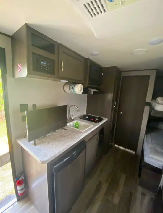 Compact RV rental interior featuring a kitchen, TV, and bunk beds. Ideal for travel adventures.. Jayco Jay Flight 2021