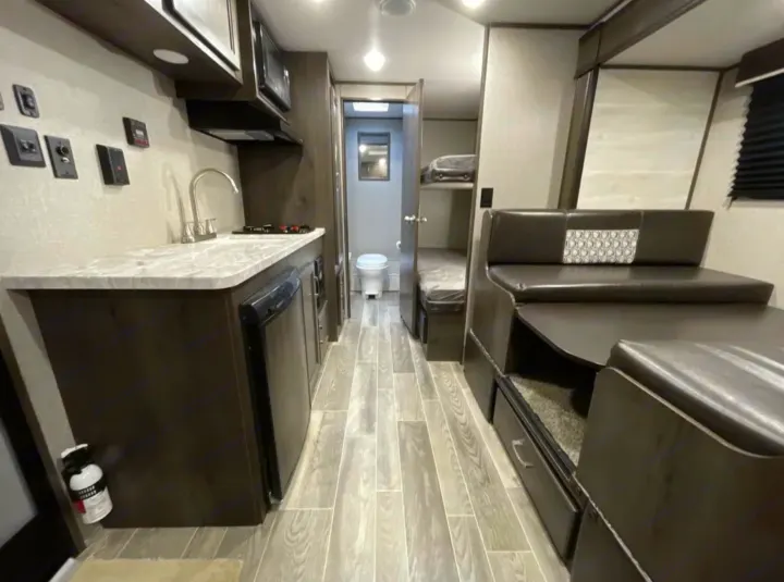 This RV rental features a cozy interior with a kitchen, dinette, bunk beds, and bathroom for comfortable travel.. Jayco Jay Flight 2021