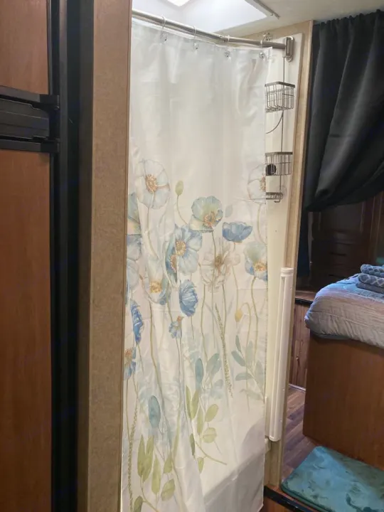 RV rental interior: floral shower curtain, wall caddy, and a glimpse of the bedroom. Compact and functional travel space.. Thor Majestic 2016