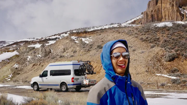 RV rental van, bikes ready for adventure in snowy mountains. Man in blue jacket smiles, enjoying the rugged landscape.. Nissan Other 2012
