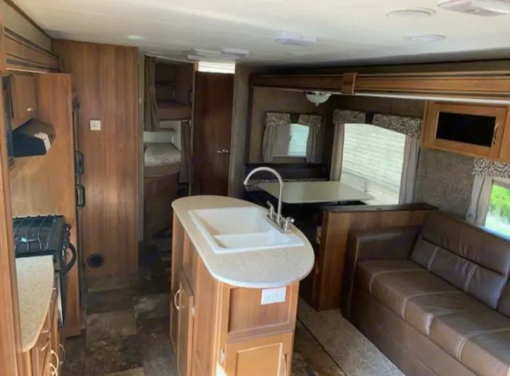 Inside an RV rental: full kitchen with island, cozy dinette, comfortable sofa, and bunk beds. Ready for travel!. Coachmen Apex 2015