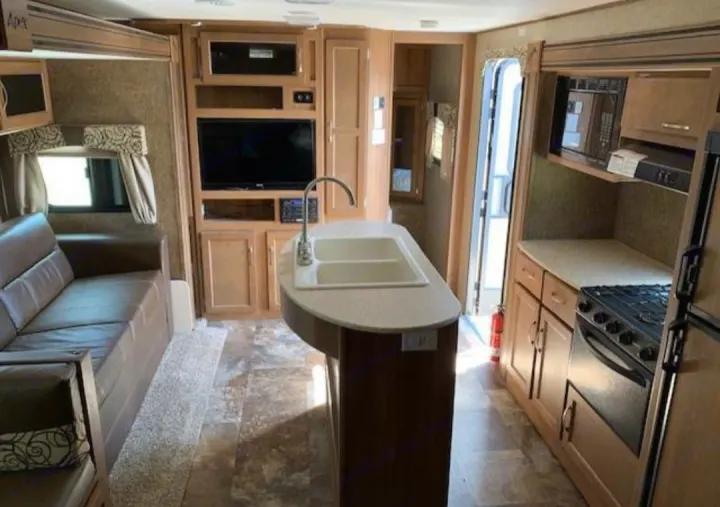 RV rental: Bright interior with kitchen island & sink, comfortable sofa, entertainment center, stove, microwave, and fridge.. Coachmen Apex 2015