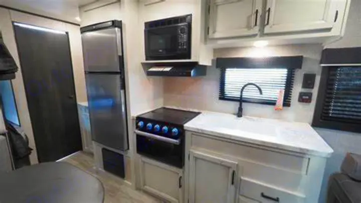 Explore a modern RV rental kitchen featuring a sink, stove, microwave, and refrigerator. Perfect for adventures.. Jayco Jay Flight SLX 2022