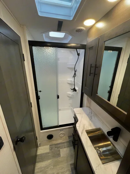 Clean RV rental bathroom featuring a glass shower, sleek sink, and modern gray flooring.. FR3 FR3 Motorhome 2023
