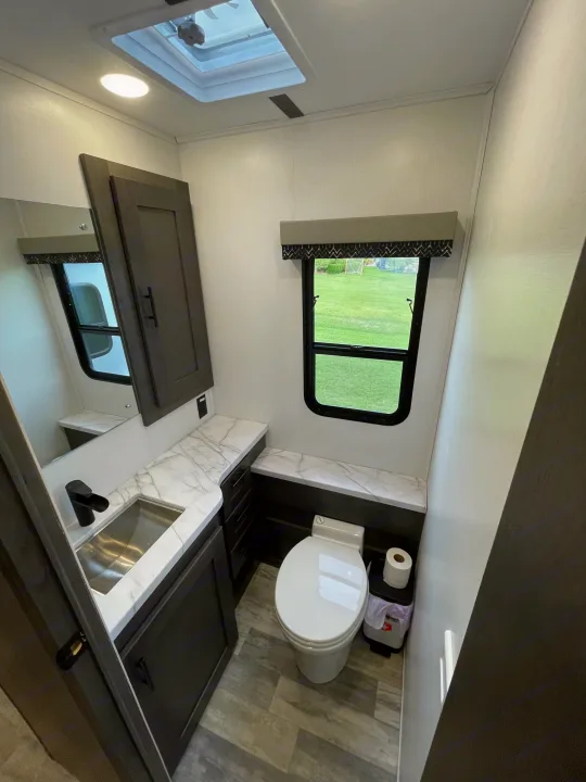Well-appointed RV rental bathroom featuring a contemporary sink, toilet, mirror, and cabinetry for comfortable camping travel.. FR3 FR3 Motorhome 2023